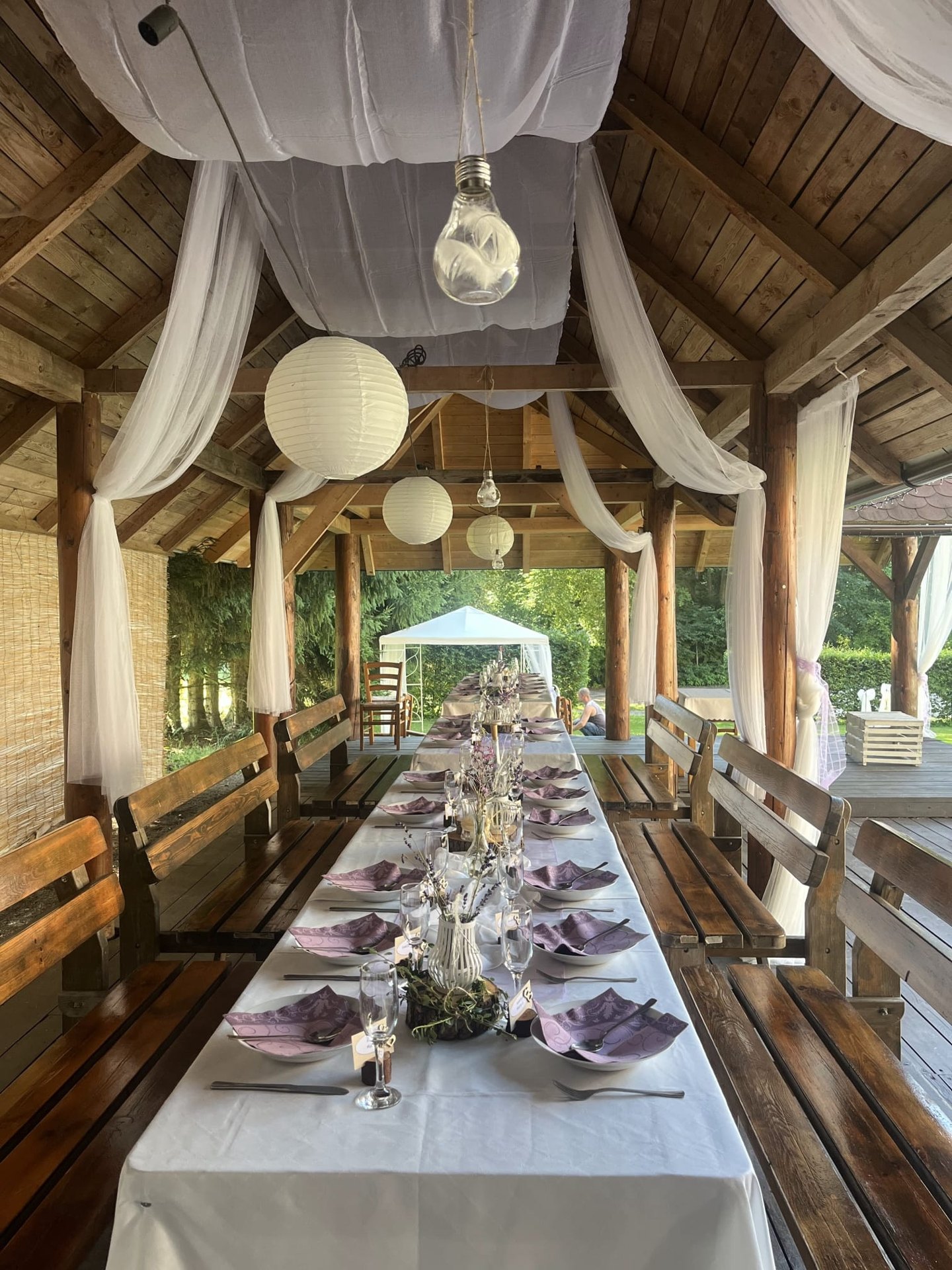 Svatebně připravený stůl pod střechou dřevěného pavilonu