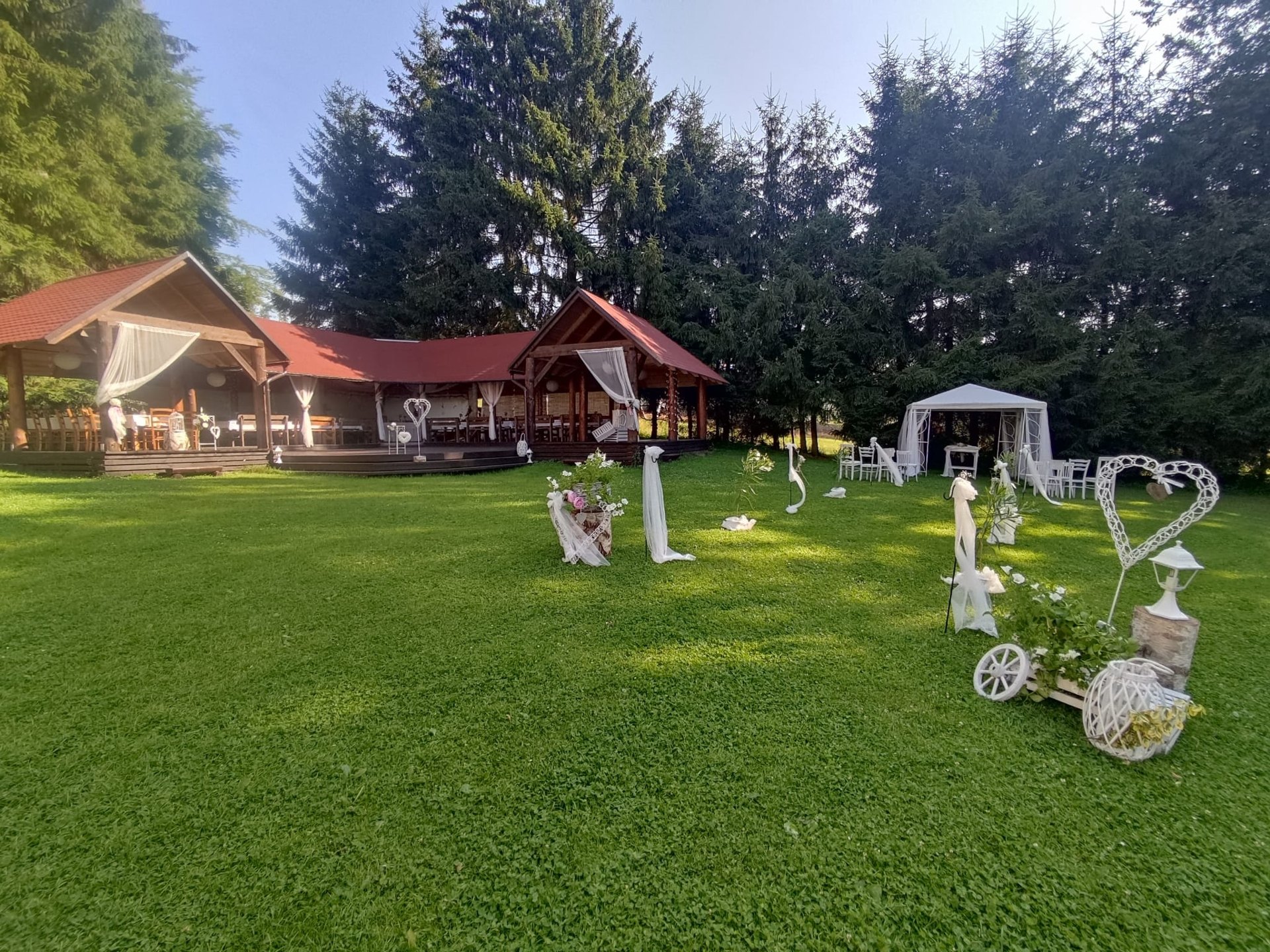 Svatební zahrada před dřevěným pavilonem a lesem